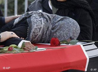 A woman mourns at the coffin with the remains of a victim killed by a fire in front of the burnt house in Ludwigshafen, Germany, Sunday, Feb. 10, 2008.