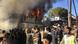 Residents of the Moria refugee camp look on as a modular home burns