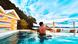 A man sips a drink in a pool overlooking the ocean. 