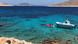 Ein Boot auf azurblauem Wasser vor der Insel Halki, Griechenland