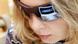 A laptop's browser displaying Facebook is reflected in a woman's sunglasses