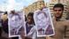 Protesters holding pictures of Mubarak with an X over his face