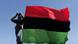 Libyan rebel looks through his binocular toward the sky, behind a waving rebel flag